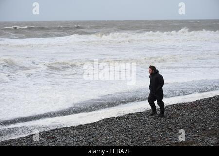 Aberystwyth, Wales, UK. 15. Januar 2015. UK-Wetter: Ein einsamer Mann geht den Strand entlang als orkanartigen Winden und stürmischer See weiterhin die Strandpromenade in Aberystwyth Wales Teig.   Hochwasserwarnungen sind für viele Flüsse in Mittel- und Nord-Wales.  mit schweren orkanartigen Winden Böen bis zu 70 km/h in Orte machen für "schwierige Reisebedingungen".   Schnee fällt auf eine höhere Ebene in Nord-Wales und Schottland. Bildnachweis: Keith Morris/Alamy Live-Nachrichten Stockfoto