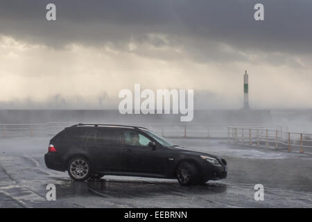 Aberystwyth, Wales, UK. 15. Januar 2015. UK Wetter: Ein Auto, geparkt auf der Promenade in Aberystwyth wie seine Insassen Sturmwellen bricht über die Hafenmauer Uhren. Bildnachweis: Alan Hale/Alamy Live-Nachrichten Stockfoto