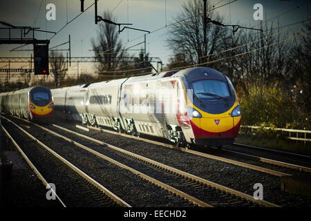 Levenshulme Bahnhof in South Manchester zwei Jungfrau Pendolino Züge geben die WCML an der Manchester an London-route Stockfoto