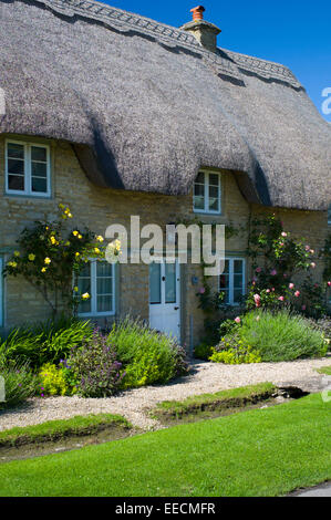 Urige traditionelle Rose bewachsenen Hütte und Stream in Minster Lovell in Cotswolds, Oxfordshire, Vereinigtes Königreich Stockfoto