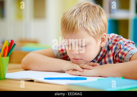 Süsser Boy Nickerchen vom Schreibtisch im Klassenzimmer Stockfoto