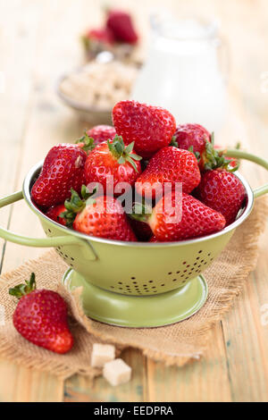 Frische Erdbeeren in Sieb auf Holztisch. Stockfoto