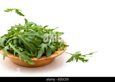 Frischer Rucola in Holzplatte. Isoliert auf weißem Hintergrund. Stockfoto