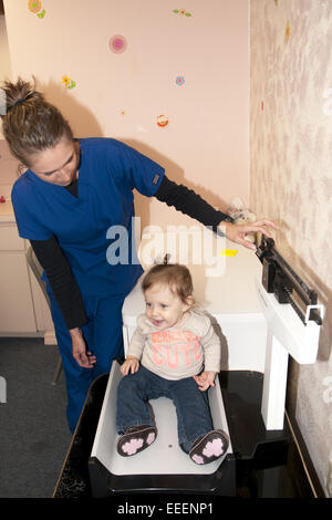 medizinisches Fachpersonal mit einem Gewicht von Kind auf eine Babywaage Stockfoto