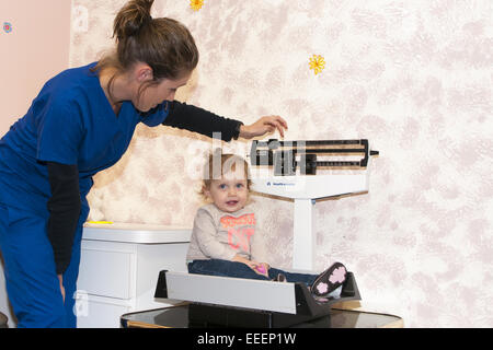 medizinisches Fachpersonal mit einem Gewicht von Kind auf eine Babywaage Stockfoto