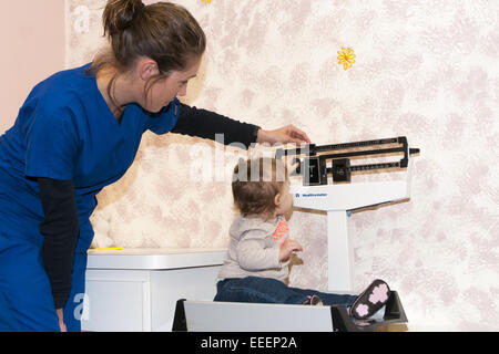 medizinisches Fachpersonal mit einem Gewicht von Kind auf eine Babywaage Stockfoto