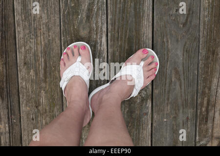Füße auf unfertige Holzoberfläche in Sandalen Stockfoto