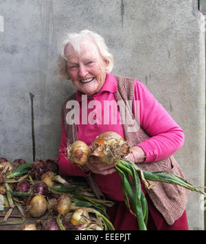 Eine ältere Dame, die ihr selbst angebauten Zwiebeln halten Stockfoto