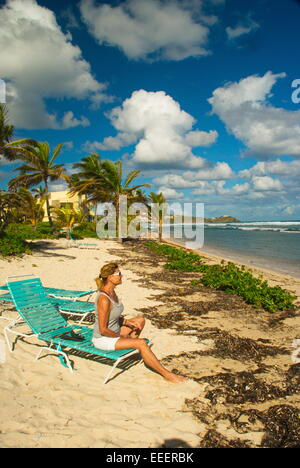 Frau sitzt auf Strand Stuhl blicken über den strahlend blauen karibischen Meer an einem sonnigen Tag auf der Insel St. Croix, USVI. Stockfoto