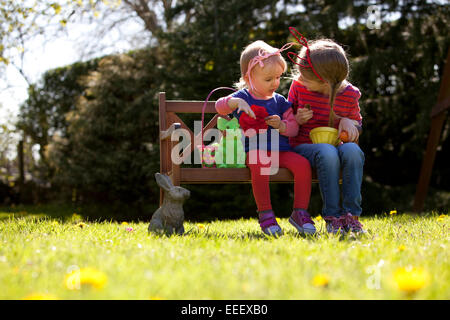 Zwei Kinder im Freien, in einem Garten Teilen Schokolade zu Ostern. Stockfoto