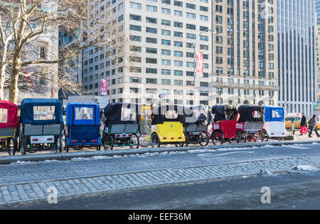 Linie der bunten dreirädrige Zyklus Taxis in Manhattan am Straßenrand gesäumt bereit Für touristische Führungen durch den Central Park, New York, im Winter Stockfoto