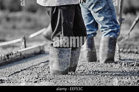 Nahaufnahme Bild von zwei Bauarbeiter stehen in frisch Beton mit hohen Gummistiefeln gegossen. Stockfoto