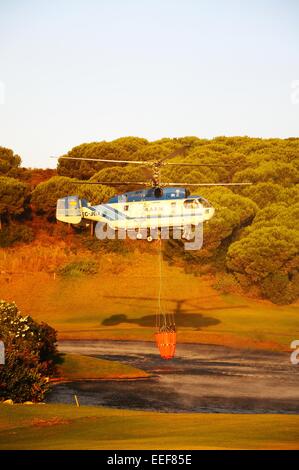 Kamov Ka-32A11BC Hubschrauber (Registrierung EG-JSQ) sammeln Wasser zur Brandbekämpfung von einem Golfplatz See Cabopino Golf. Stockfoto