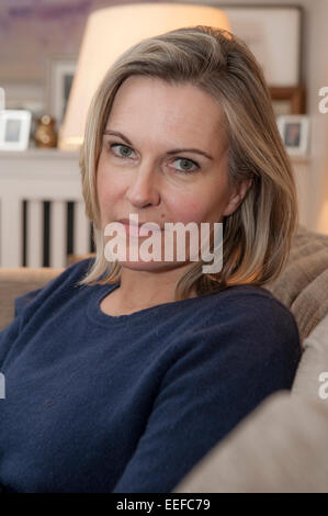 Eine Dame auf dem Sofa mit ihrem Haustier Hund, einen kleinen schwarzen Cockapoo Welpen Stockfoto