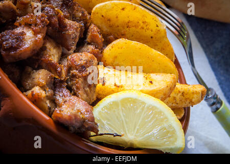 Tiefe gebratenes Schweinefleisch mit Pommes Frites und Zitrone serviert im Tontopf Stockfoto