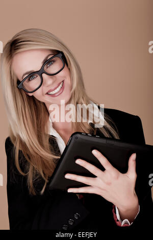 Eine attraktive blonde Geschäftsfrau hält einen schwarzen Tablet-Computer. Blonde Unternehmerin. Stockfoto