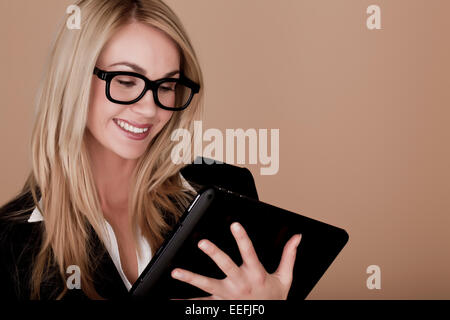 Eine attraktive blonde Geschäftsfrau hält einen schwarzen Tablet-Computer. Blonde Unternehmerin. Stockfoto