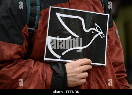 Freiburg, Deutschland. 17. Januar 2015. Ein Mann hält ein Schild, das eine Taube mit einem Bleistift auf einer Solidaritätskundgebung für "Charlie Hebdo" in Freiburg, Deutschland, 17. Januar 2015 zeigt. Polizeiberichten zufolge nahmen rund 400 Personen an der Kundgebung zum Gedenken an die Opfer von Terror-Anschlag auf französischen satirischen "Charlie Hebdo" am 7. Januar 2015. Die Aleviten kulturelle Union und die interkulturelle sammeln "Faerbung' (wörtl. Färbung) aus Freiburg für die Veranstaltung genannt. Foto: PATRICK SEEGER/Dpa/Alamy Live News Stockfoto