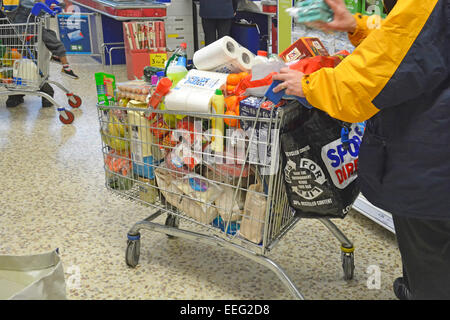 Shopper & Nahaufnahme des kompletten Einkaufswagens, der eine Woche vor Weihnachten im Osten Londons, England, im Tesco Supermarkt-Einkaufswagen überläuft Stockfoto