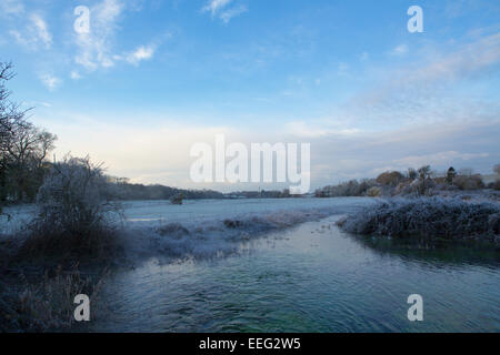 Kalt und frostig-Szene. Kleiner Fluss, der durch ein Feld mit gefrorenen Vegetation im Vordergrund. Stockfoto