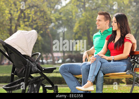 Junge Eltern mit ihrem Baby im Park auf einer Bank sitzend Stockfoto