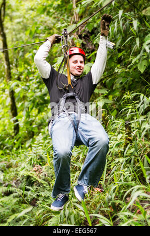 Erwachsene männliche Touristische legere Kleidung auf Zip Line oder Vordach im ecuadorianischen Regenwald erleben Stockfoto