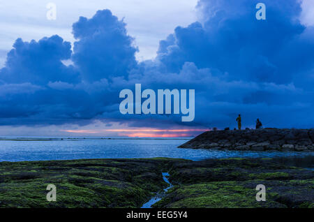 Fischer inne, um den Sonnenuntergang am Sunabe Beach in Okinawa, Japan. Stockfoto
