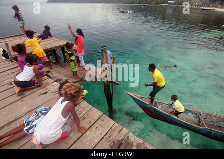 Menschen und Kinder spielen und Fischerei vor der Anlegestelle in Yenbeser Dorf, Gam Insel, Raja Ampat, Provinz Papua, Indonesien. Kein Herr Stockfoto