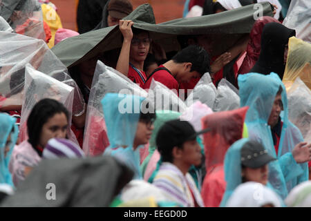 Manila, Philippinen. 18. Januar 2015. Menschen tragen Regenmäntel bei Regen gebracht tropischer Sturm Mekkhala während einer Messe in Manila, Philippinen, 18. Januar 2015. Mindestens 2.000 Familien wurden evakuiert in sechs Provinzen in Zentral-Philippinen als tropischer Sturm Mekkhala, lokal bekannt als Amang, zerschlagen das Land, die Staat Disaster Management Agency, sagte am Sonntag. Bildnachweis: Rouelle Umali/Xinhua/Alamy Live-Nachrichten Stockfoto