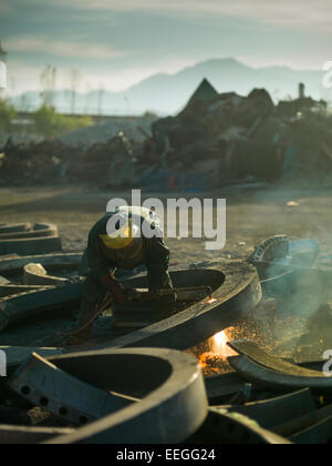 männliche Arbeiter Ohrschutz Schweißen Metall im recycling-center Stockfoto