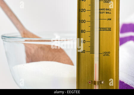 Zucker oder Marmelade Thermometer neben Schüssel Zucker mit lila und weißen Tuch im Hintergrund Stockfoto