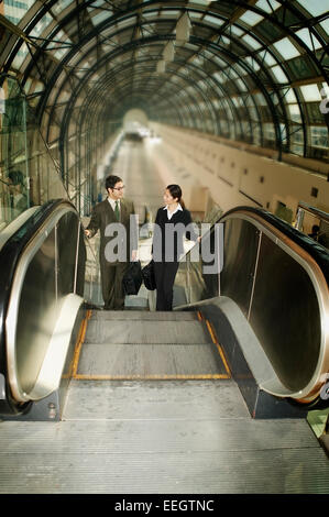 Geschäft paar sprechen auf Rolltreppe Stockfoto