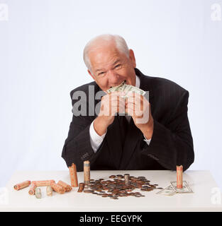 Reifer Mann im Anzug isst Währung USD Stockfoto