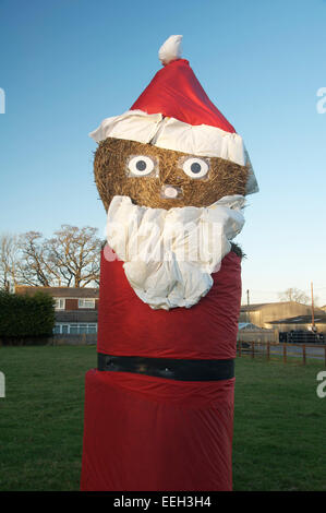 Happy Xmas. Eine große komische Figur des Santa Claus aus Heuballen. Es ist ein eigenwilliges Weihnachtszeit in der Landschaft von Dorset. England, UK. Stockfoto