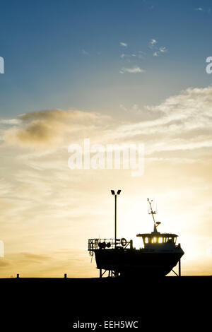 Angelboot/Fischerboot auf dem Festland bei Sonnenaufgang im Hafen von Lindisfarne, Holy Island, Northumberland, England. Silhouette Stockfoto