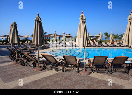 Chaiselongue und Sonnenschirme am Pool. Stockfoto