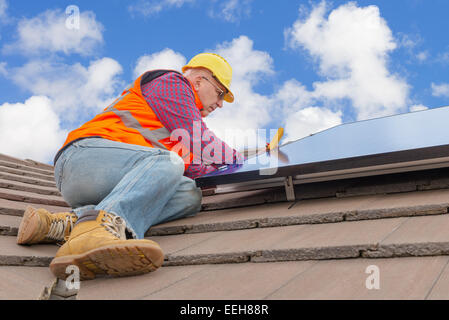 erfahrene Arbeiter überprüfen Sonnenkollektoren auf dem Hausdach Stockfoto