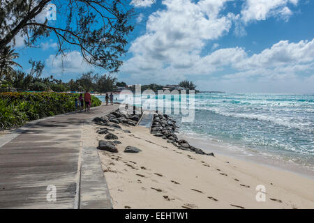 Touristen zu Fuß entlang der Promenade in Accra Beach an der Südküste der karibischen Insel Barbados - nur zur redaktionellen Nutzung Stockfoto