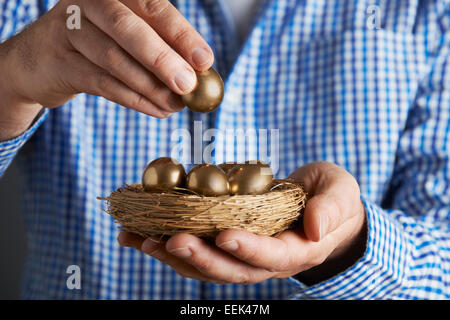 Mann hält Nest voller goldenen Eiern Stockfoto