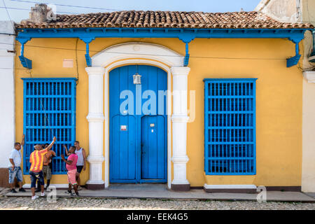 Junge kubanische Männer sammeln und außerhalb eine bunt bemalte Gebäude auf der Plaza Mayor, Trinidad, Kuba zu sprechen. Stockfoto