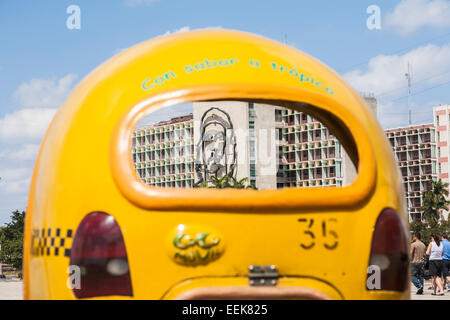 Gelbe coco Taxi an das Ministerium des Innern Gebäude geparkt mit Bild von Che Guevara an der Plaza de la Revolución, Havanna, Kuba Stockfoto