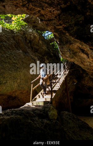Frau, die eine Treppe durch eine Höhle hinuntergeht, um zum Padang Padang Beach in Labuan Sait, South Kuta, Bali, Indonesien zu gelangen. Stockfoto