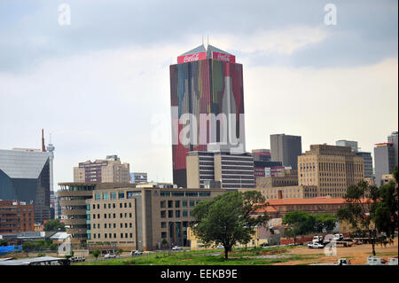 Aus der Ferne betrachtet ein Coca Cola bedeckt Wolkenkratzer in Johannesburg Central Business District. Stockfoto