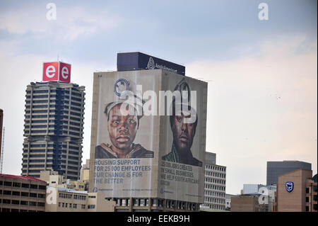 Die Gesichter der Bergleute auf einem Wolkenkratzer in der Innenstadt von Johannesburg betrachtet aus der Ferne. Stockfoto