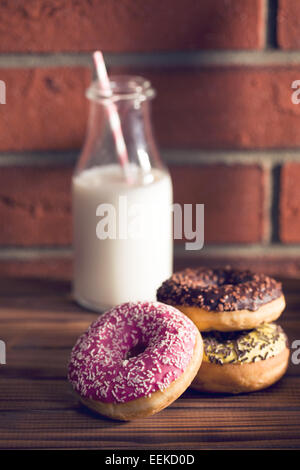 verschiedene Donuts auf Holztisch vor der Mauer Stockfoto