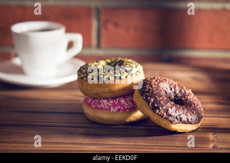 verschiedene Donuts auf Holztisch vor der Mauer Stockfoto