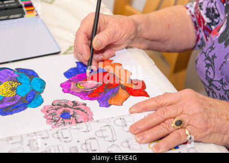 ältere Frau mit Buntstiften in einem Malbuch beschäftigt Stockfoto