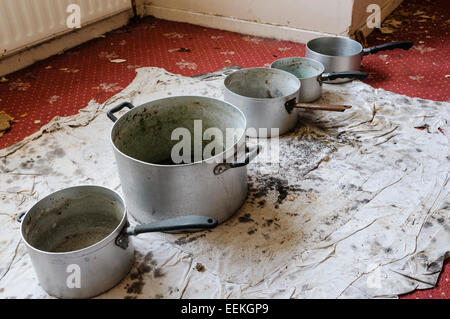 Töpfe, aufgereiht auf einem Teppich, Wasser aus einem undichten Decke fangen Stockfoto