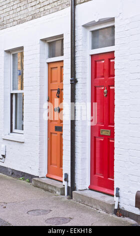 Rot und orange Haustüren auf angrenzenden terrassenförmig angelegten Häuser in Großbritannien Stockfoto