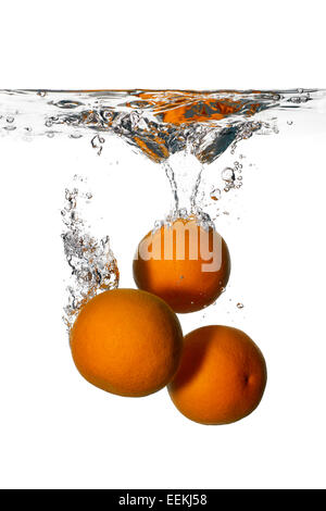 Nahaufnahme von drei Orangen fallen in frisches und sauberes Wasser isoliert auf weißem Hintergrund. Waschen Sie die Früchte Stockfoto